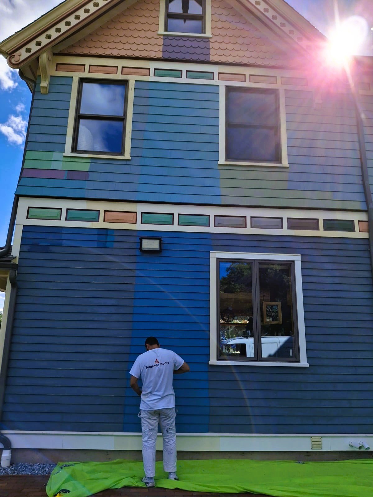 A DDP painter finishing the exterior of a New England Victorian home